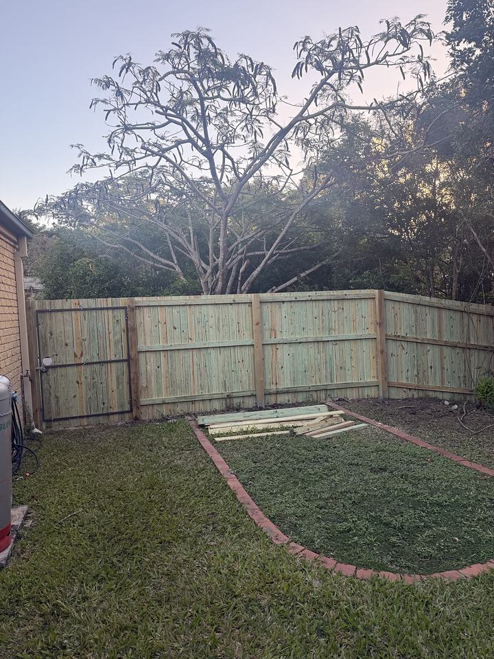 Timber paling fence enclosing a back yard, two runs meeting at a corner