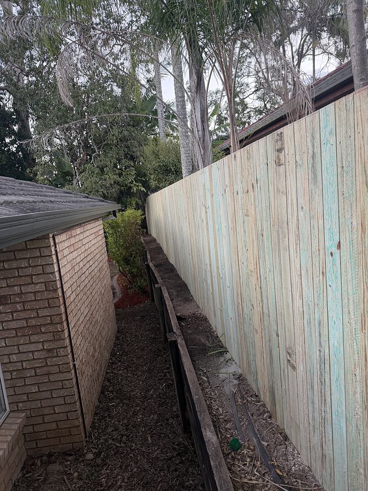Timber paling fence built in a narrow gap between a brick wall and a boundary